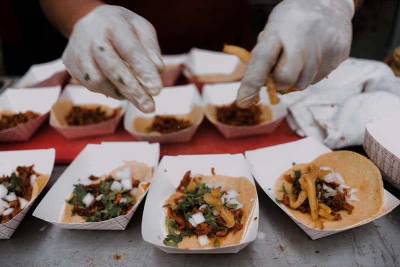 Gloved hands plating tacos for an event